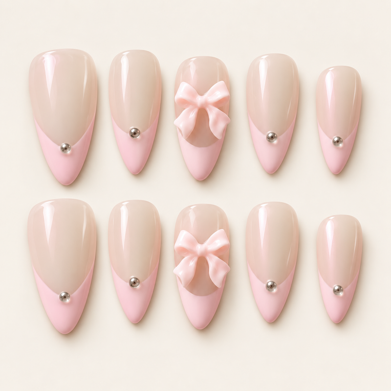 Ensemble de 10 faux ongles amande nude nacré et French rose pastel, décorés de nœuds roses 3D et de détails argentés, sur fond ivoire.