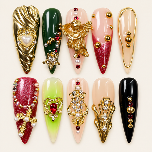 10 press-on nails Ruby longs et pointus, rouges, verts, noirs et roses, avec ange doré, cœurs, croix, perles et pierres décoratives sur fond ivoire.